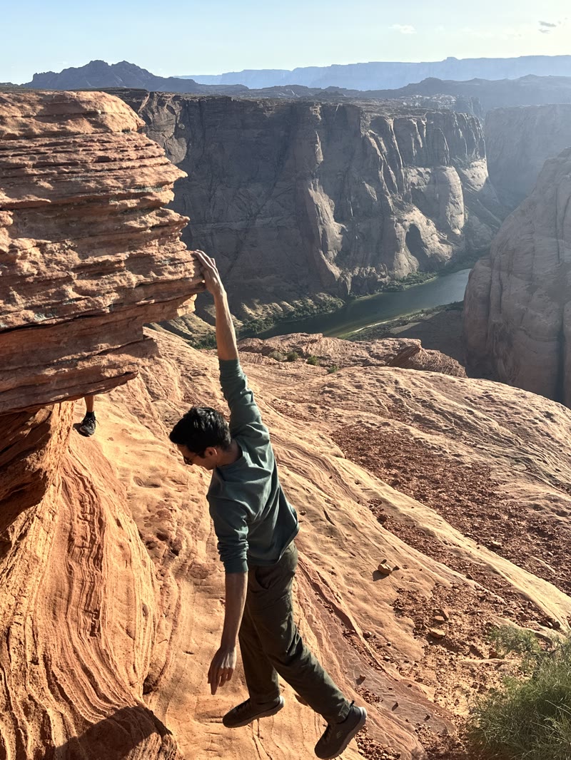 Teja climbing beneath a rock overhang above a canyon